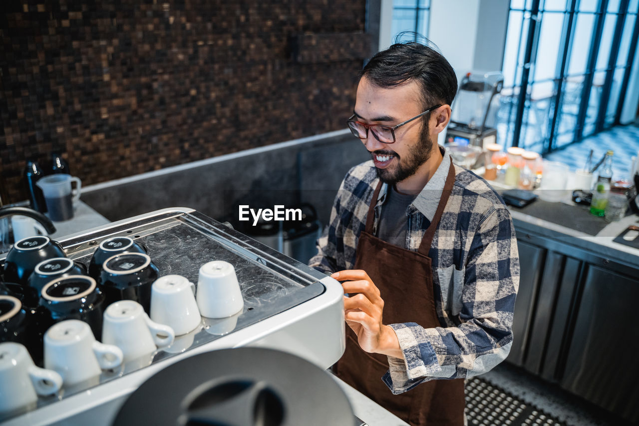 Smiling man preparing coffee in cafe