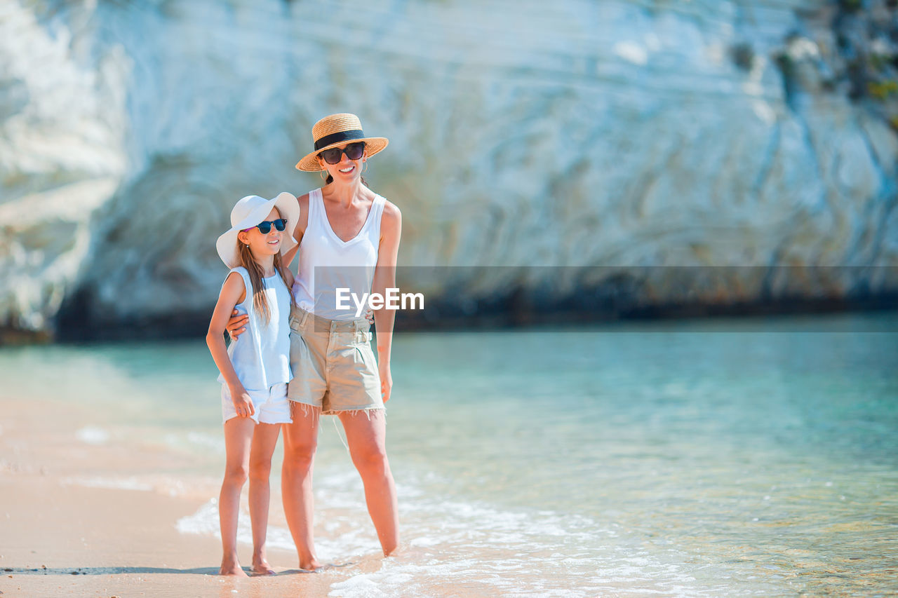 Full length of mother and daughter standing on beach