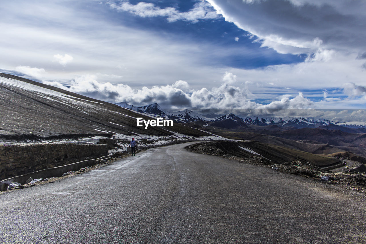 PANORAMIC VIEW OF ROAD LEADING TOWARDS SNOWCAPPED MOUNTAIN AGAINST SKY