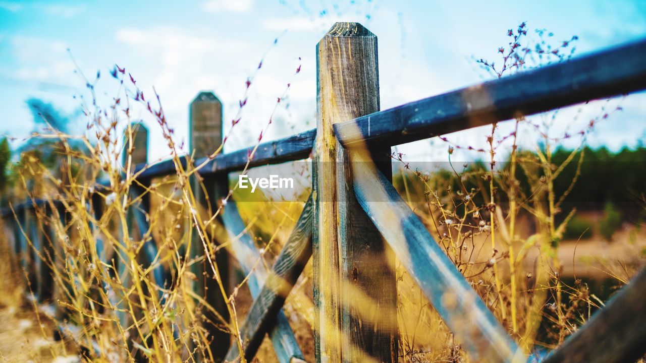 CLOSE-UP OF FENCE ON FIELD AGAINST SKY