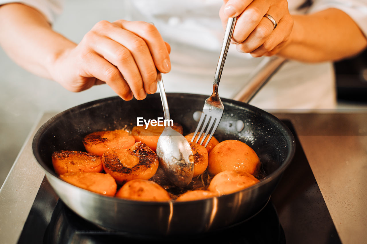 Hands are turning around fried apricots for confiture