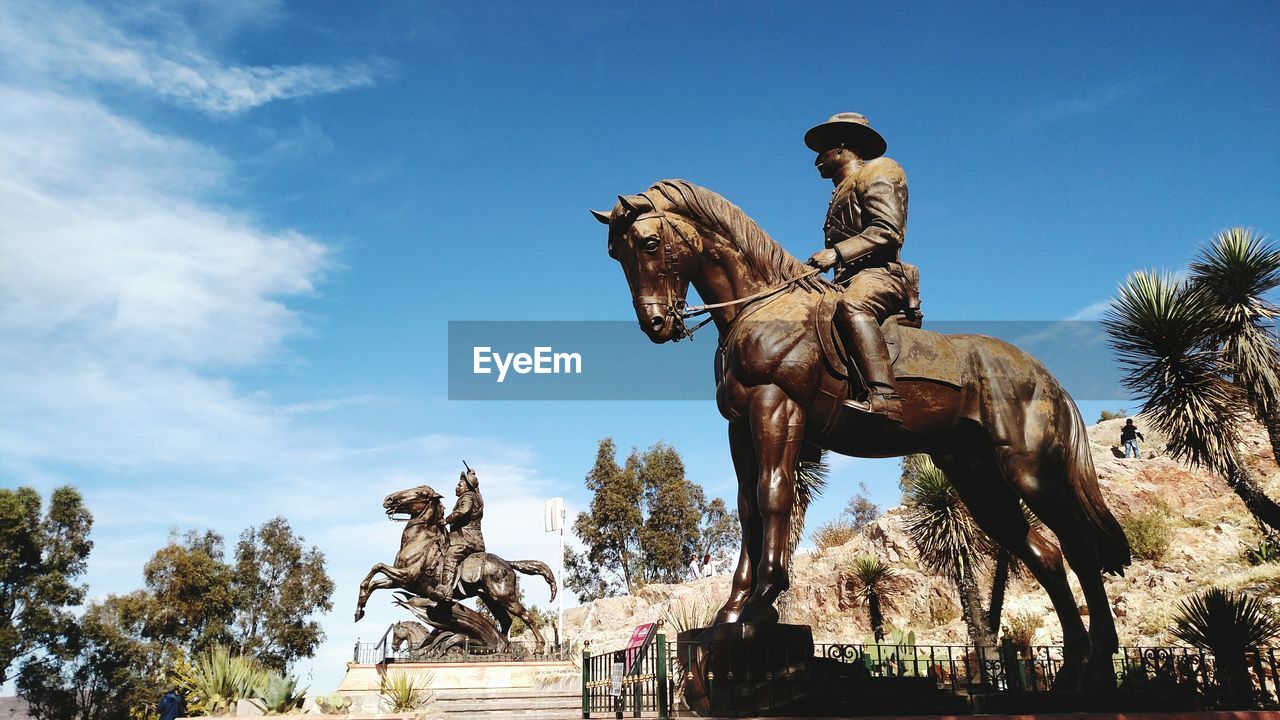 Low angle view of statues against blue sky