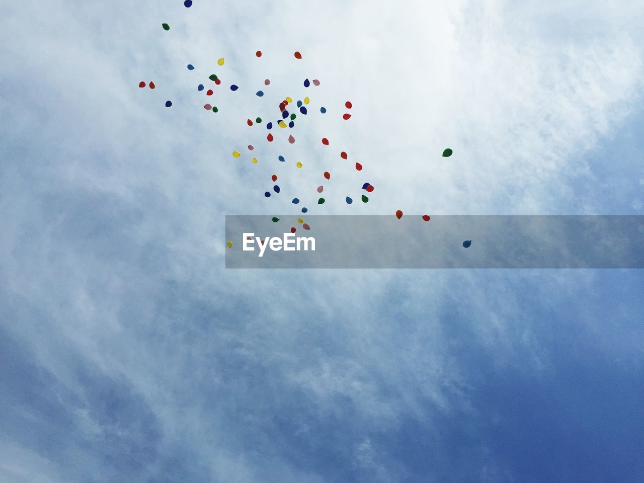 Low angle view of colorful balloons flying against sky