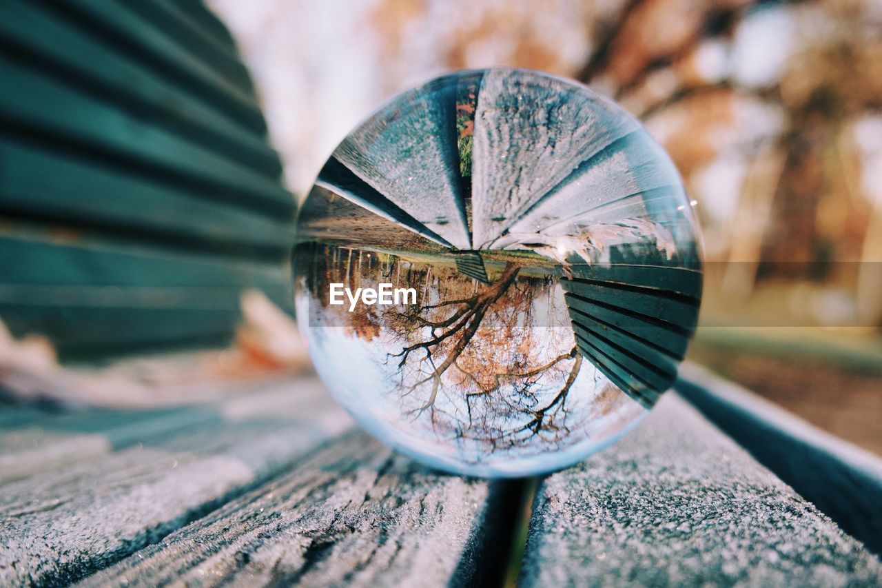 Close-up of crystal ball on wooden bench 