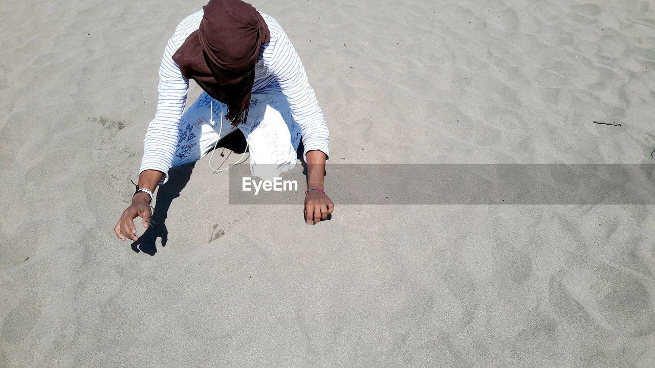 Unrecognizable person kneeling on sand