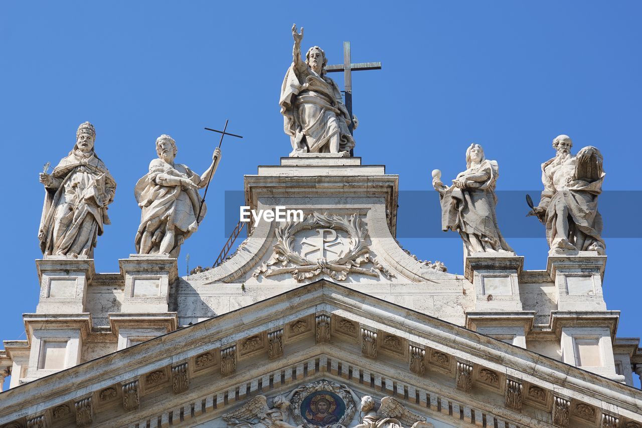 Low angle view of statues on church against sky