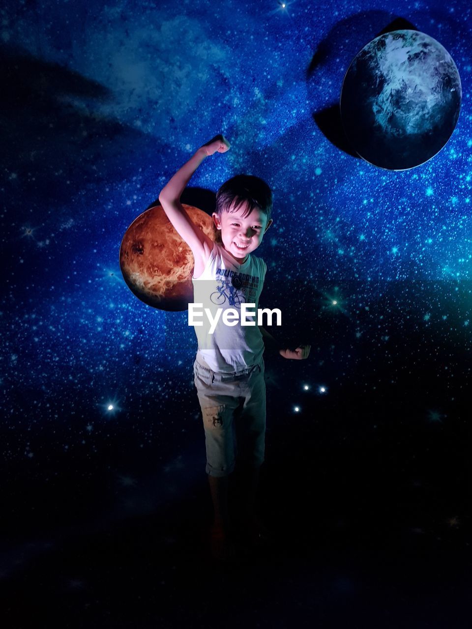 Digital composite image of boy standing against star field at night