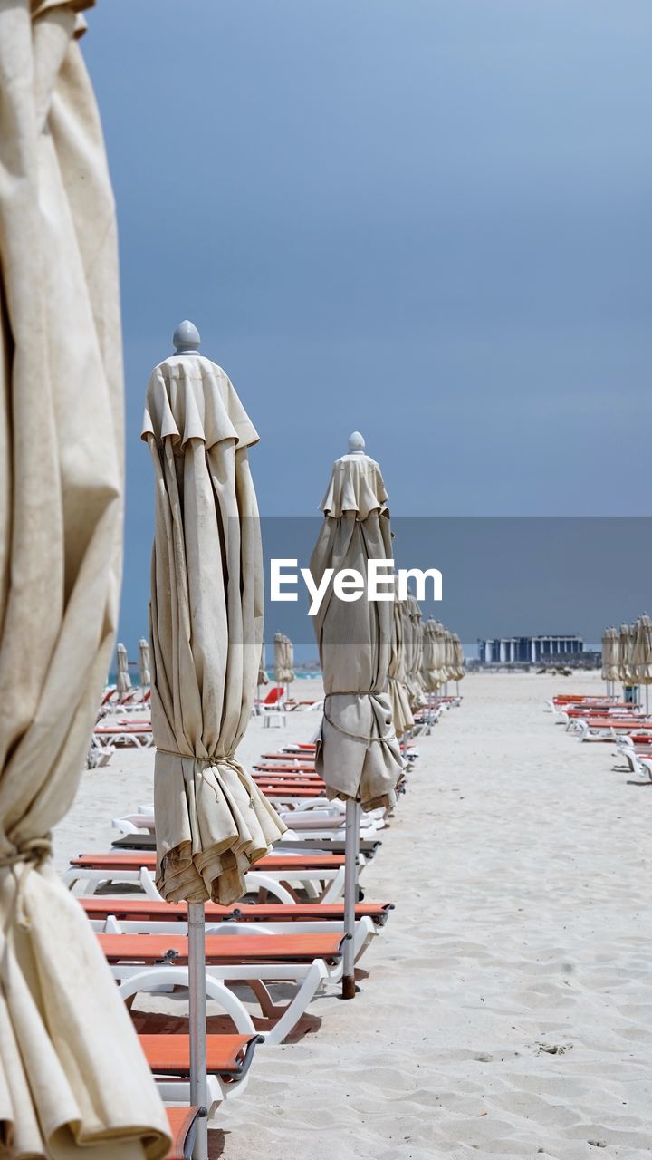 Rear view of umbrellas on beach against clear sky