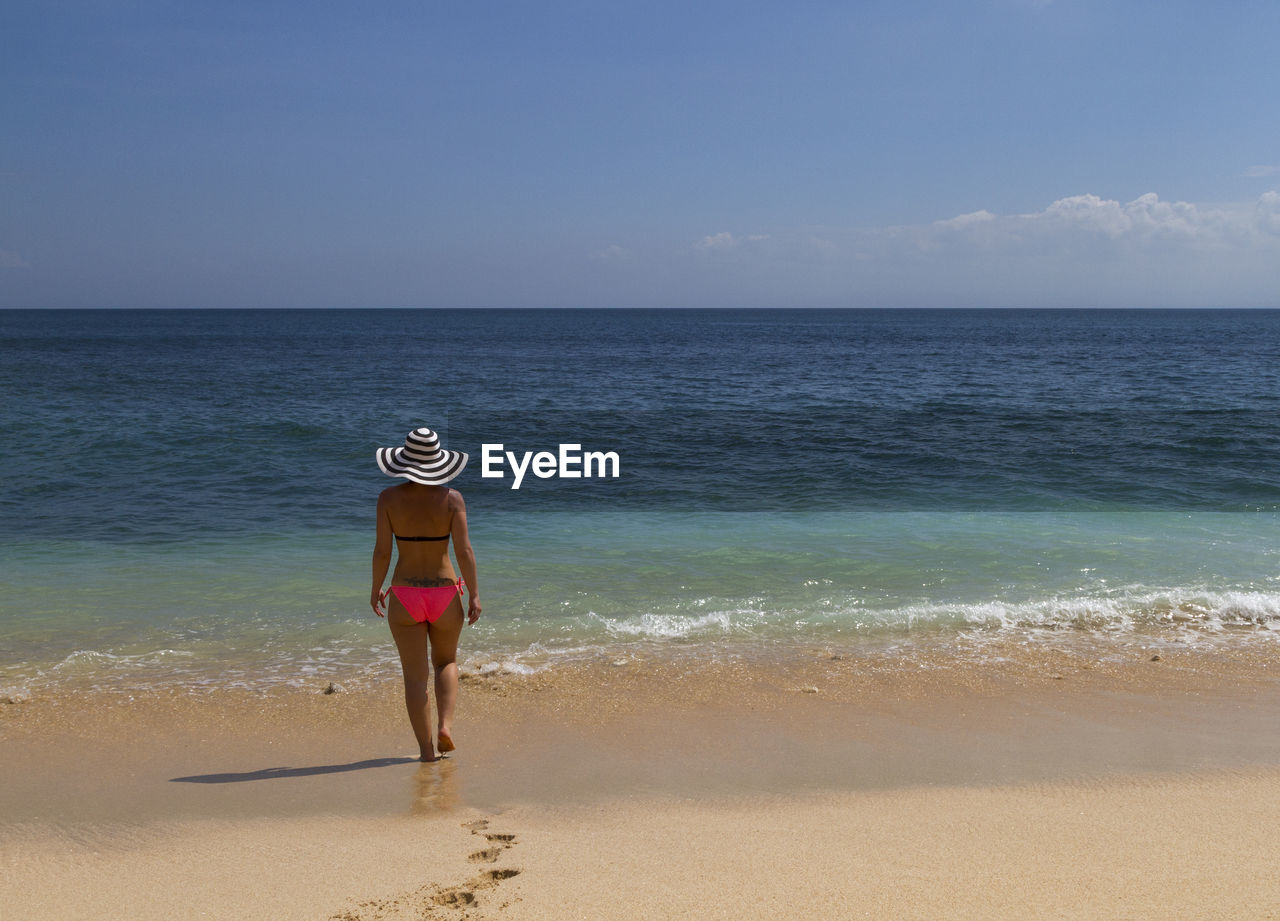 Full length of woman walking at beach against sky