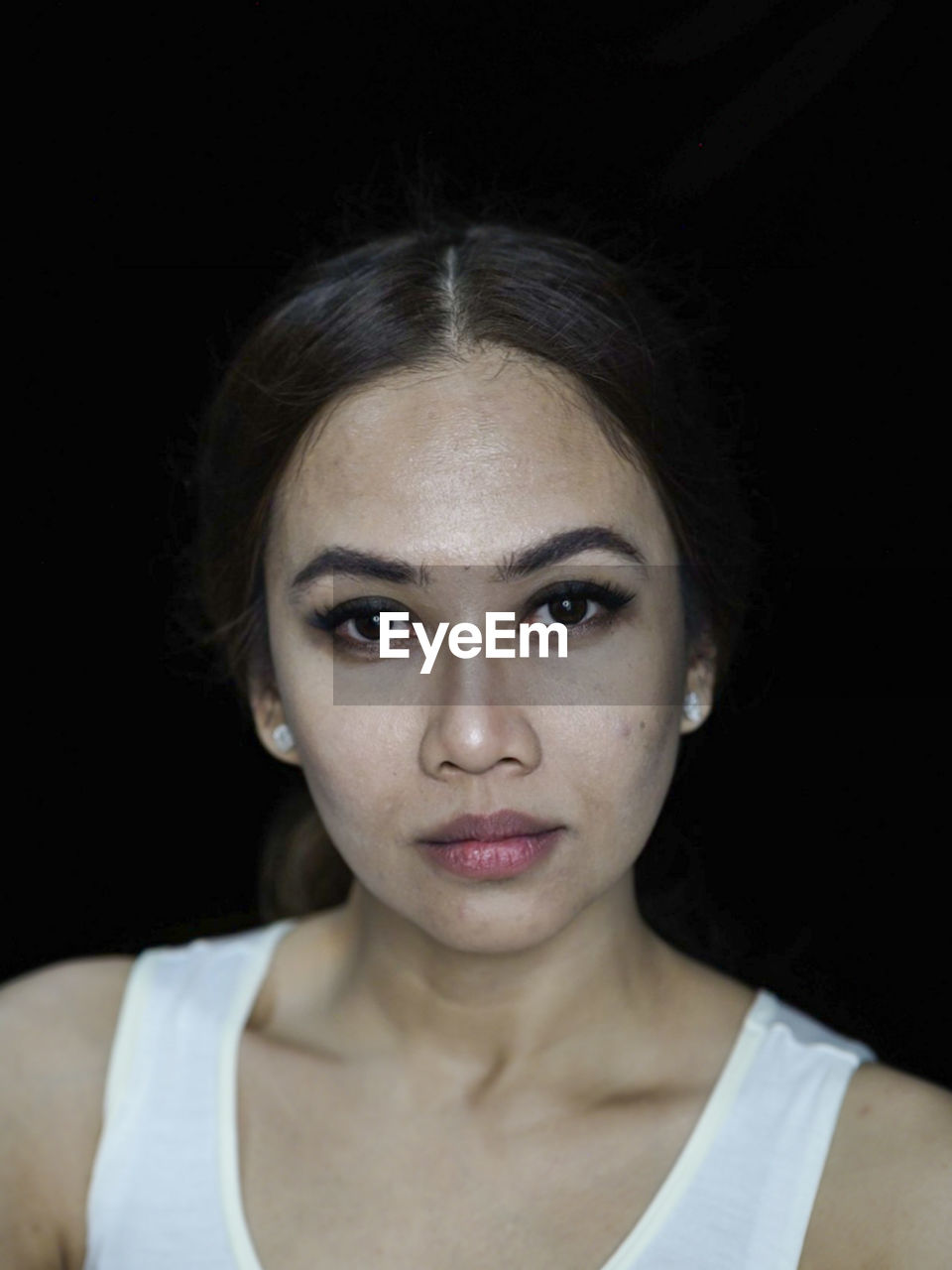 Close-up portrait of young woman against black background