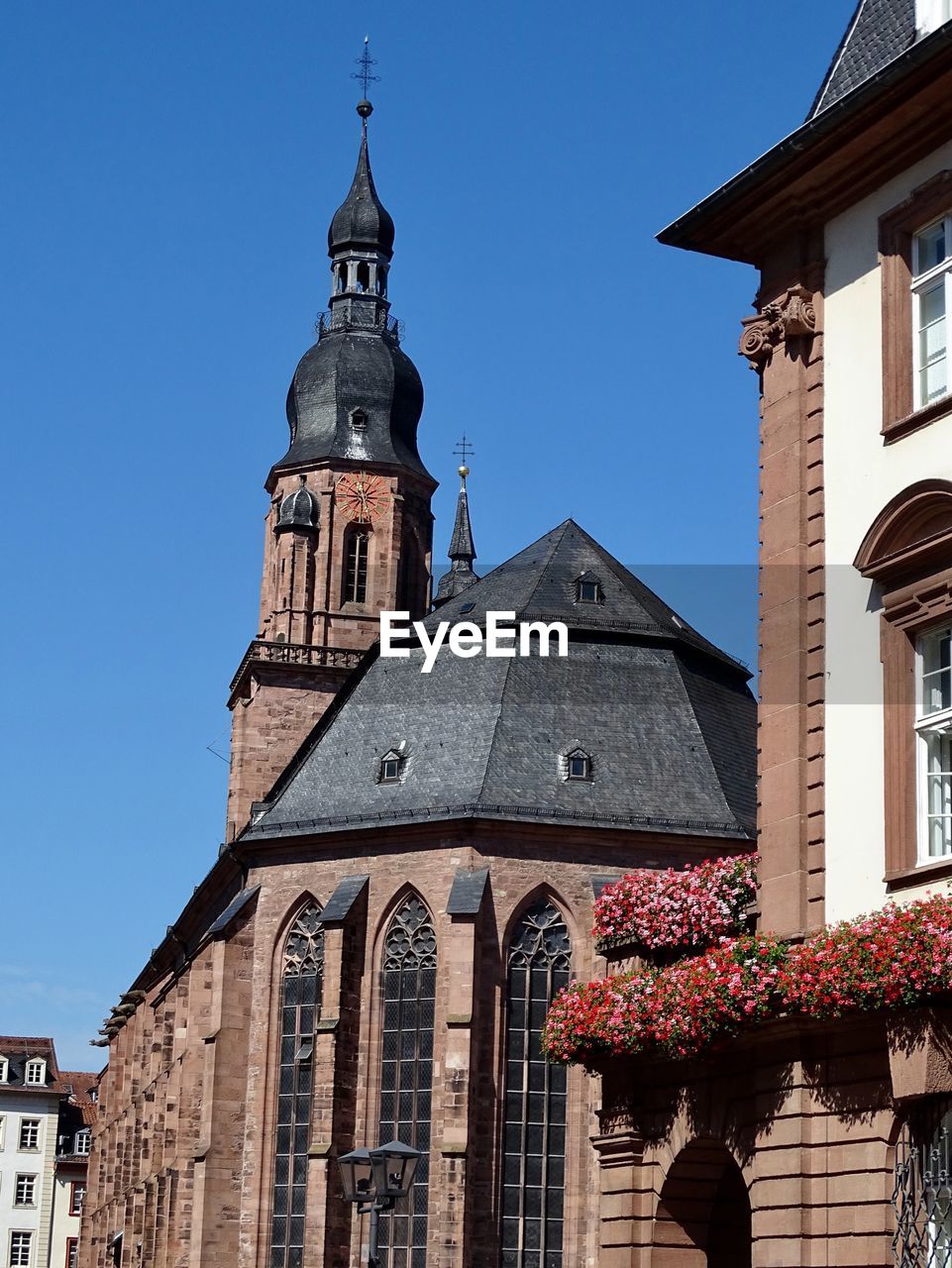 Low angle view of clock tower amidst buildings in germany against blue sky