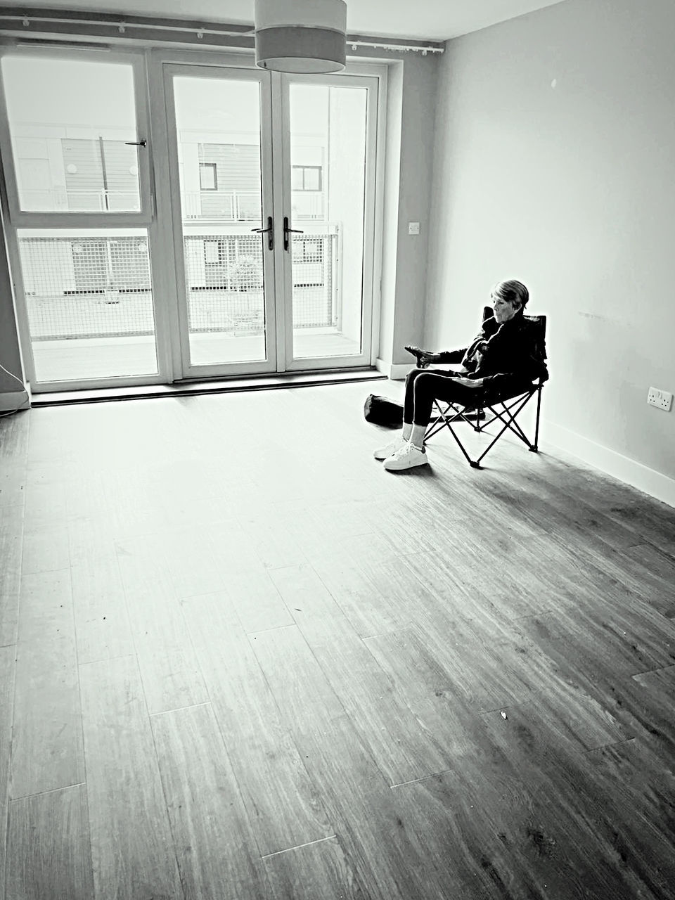 white, black, floor, indoors, flooring, black and white, monochrome, one person, light, home interior, full length, monochrome photography, house, window, adult, laminate flooring, wood flooring, sitting, hardwood floor, interior design, architecture, loneliness, wood, hardwood, seat, home, person, relaxation, chair, door, lifestyles, entrance, furniture, day, side view