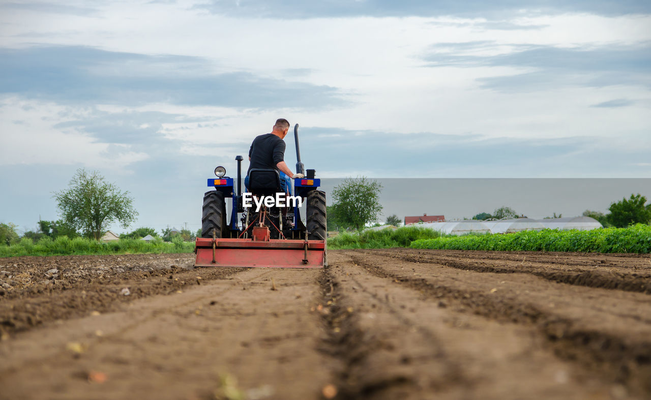 A farmer drives a tractor and cultivates an agricultural field. milling soil, cutting rows.