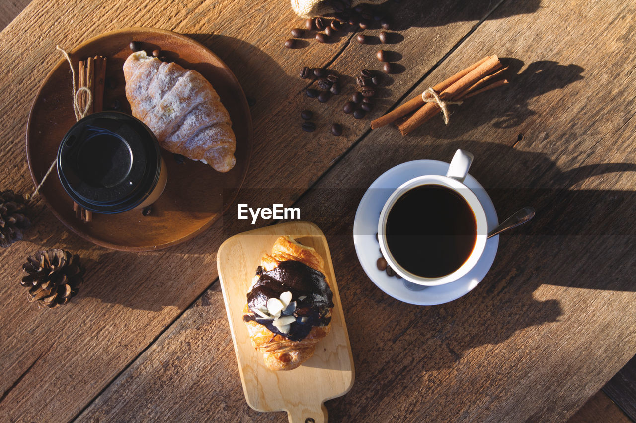 food and drink, drink, coffee, cup, food, wood, refreshment, table, mug, high angle view, coffee cup, freshness, hot drink, sweet food, directly above, meal, no people, baked, crockery, tea, breakfast, still life, kitchen utensil, fruit, eating utensil, healthy eating, indoors, sunlight, nature, spoon, black coffee, sweet, dairy