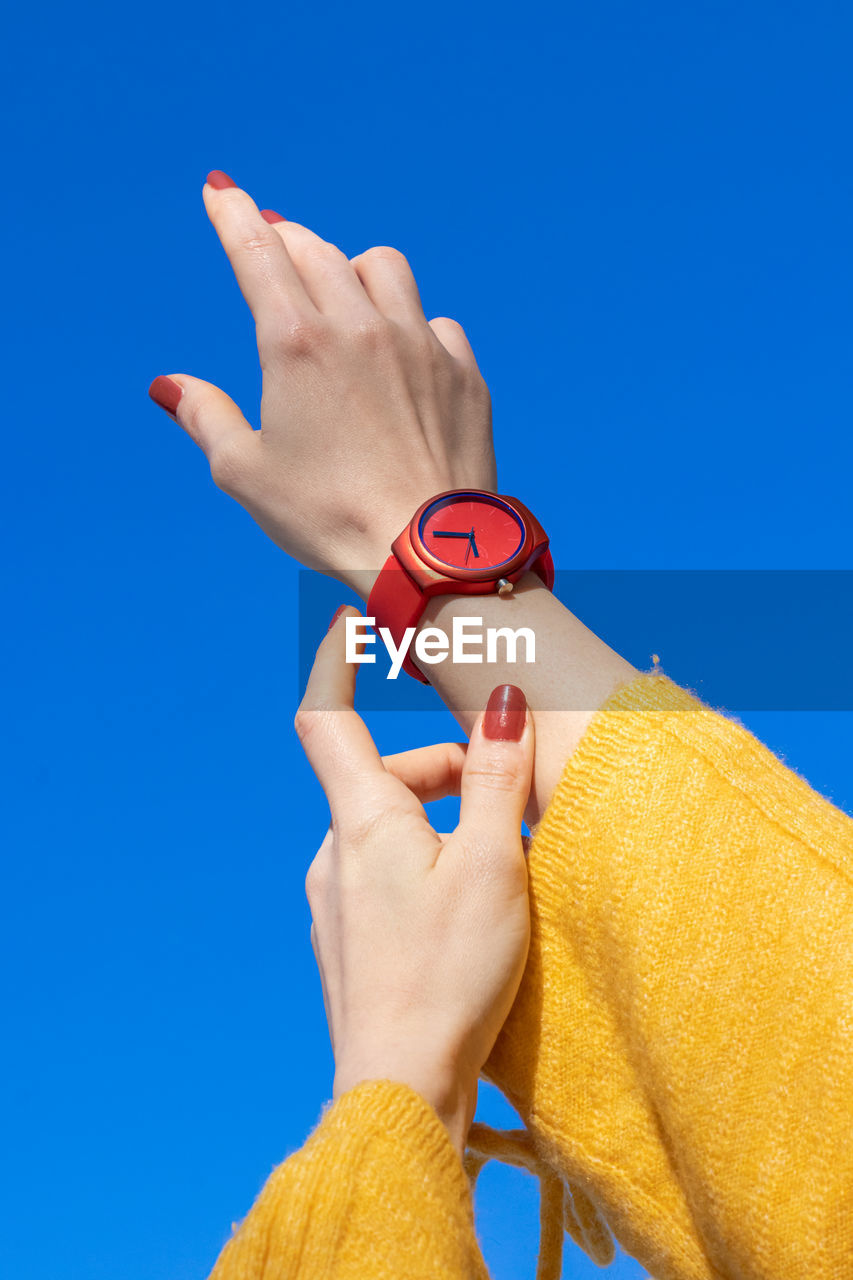 Cropped hand of person holding key against blue background