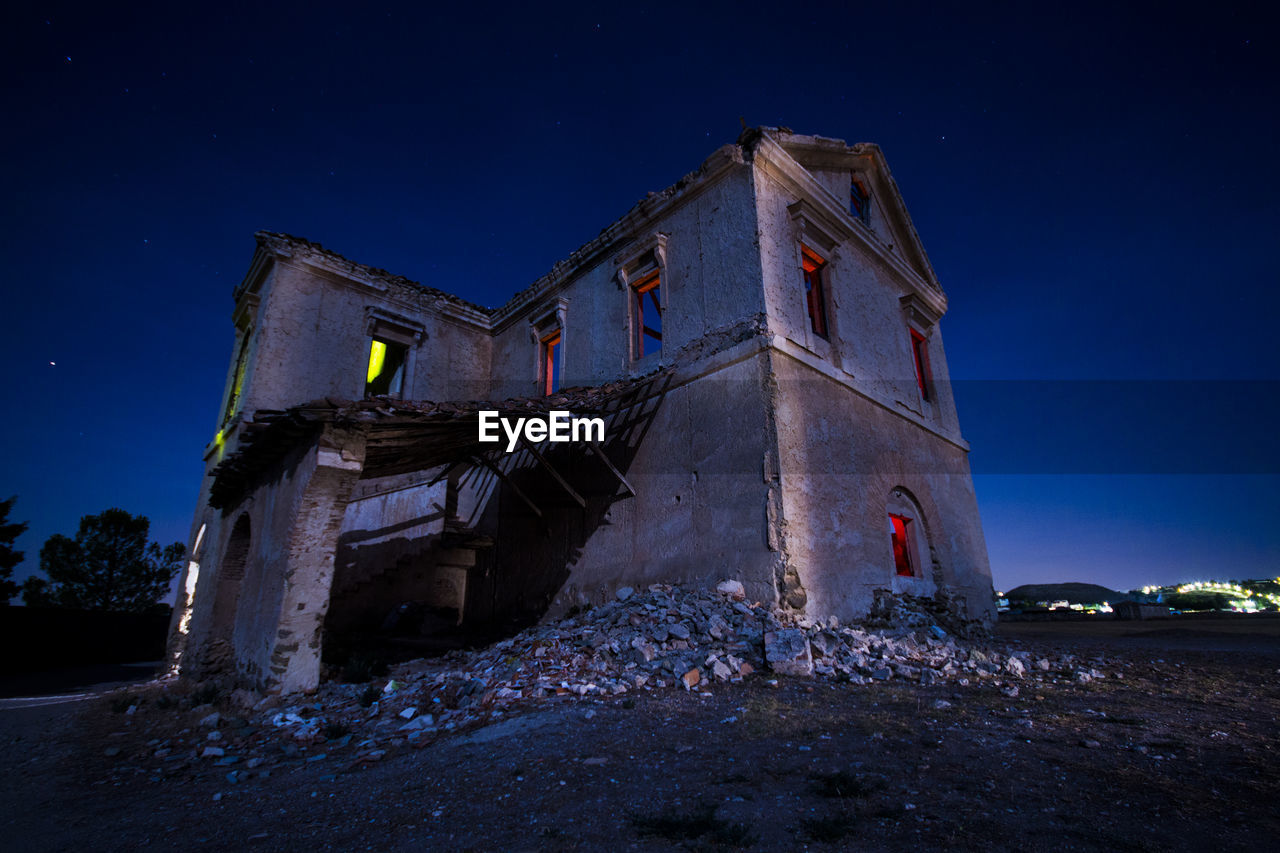 Low angle view of abandoned building against sky at night