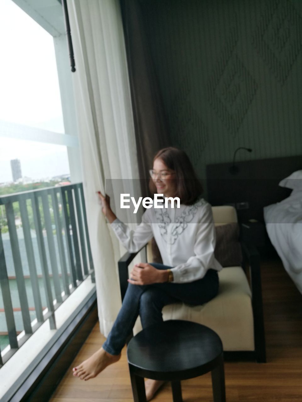 PORTRAIT OF YOUNG WOMAN SITTING ON CHAIR IN OFFICE