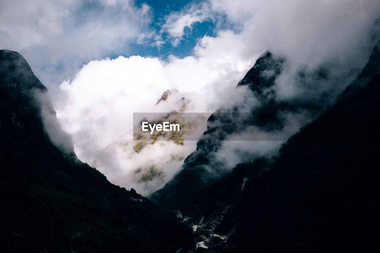 LOW ANGLE VIEW OF CLOUDS OVER MOUNTAIN AGAINST SKY