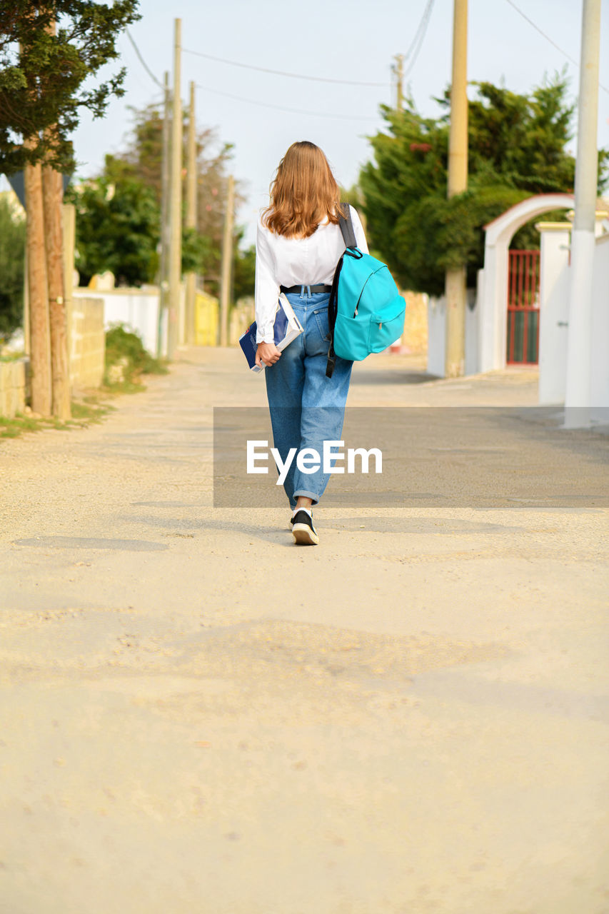 Rear view of girl walking on footpath in city
