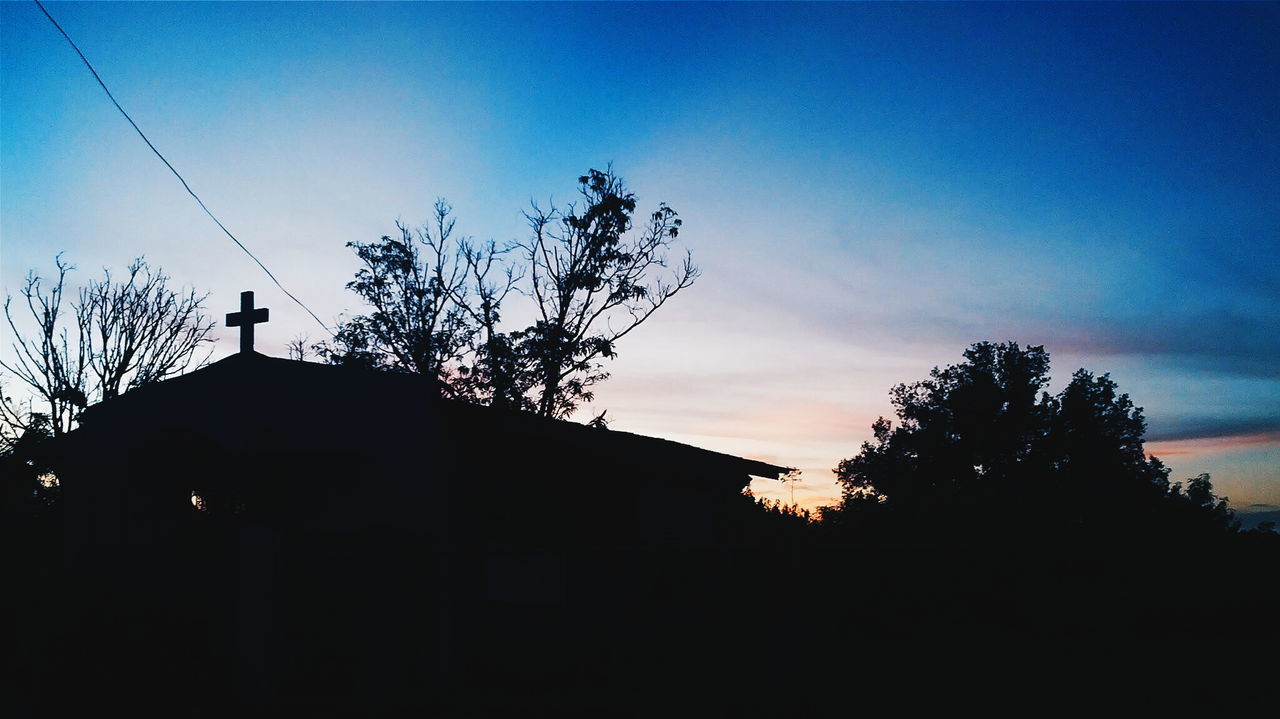 Silhouette church by trees on field against sky