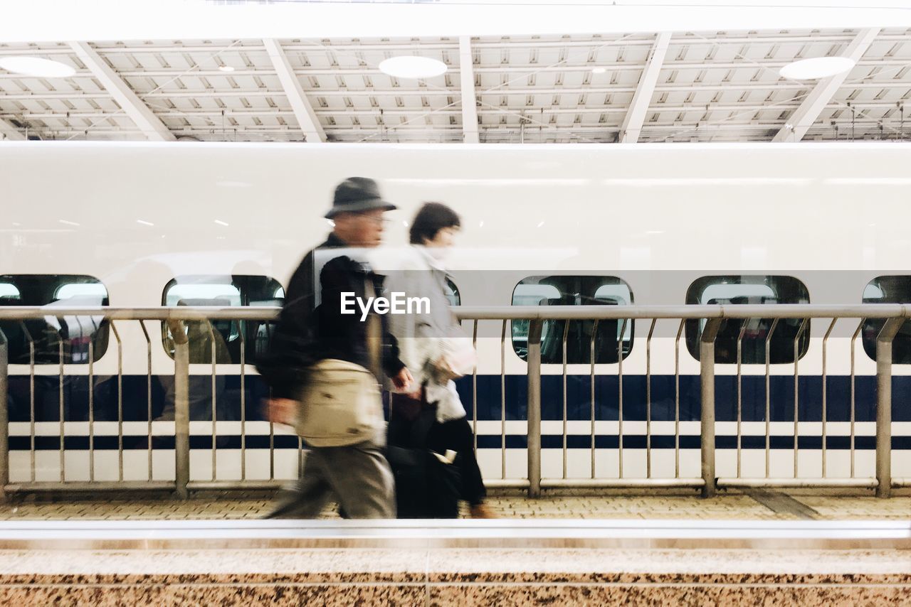 People walking at railroad station against train