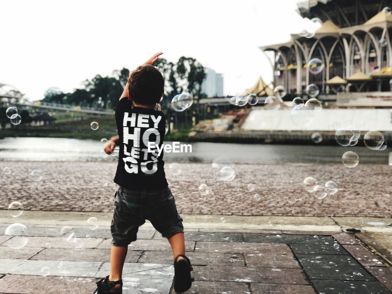 REAR VIEW OF BOY STANDING AT CITY