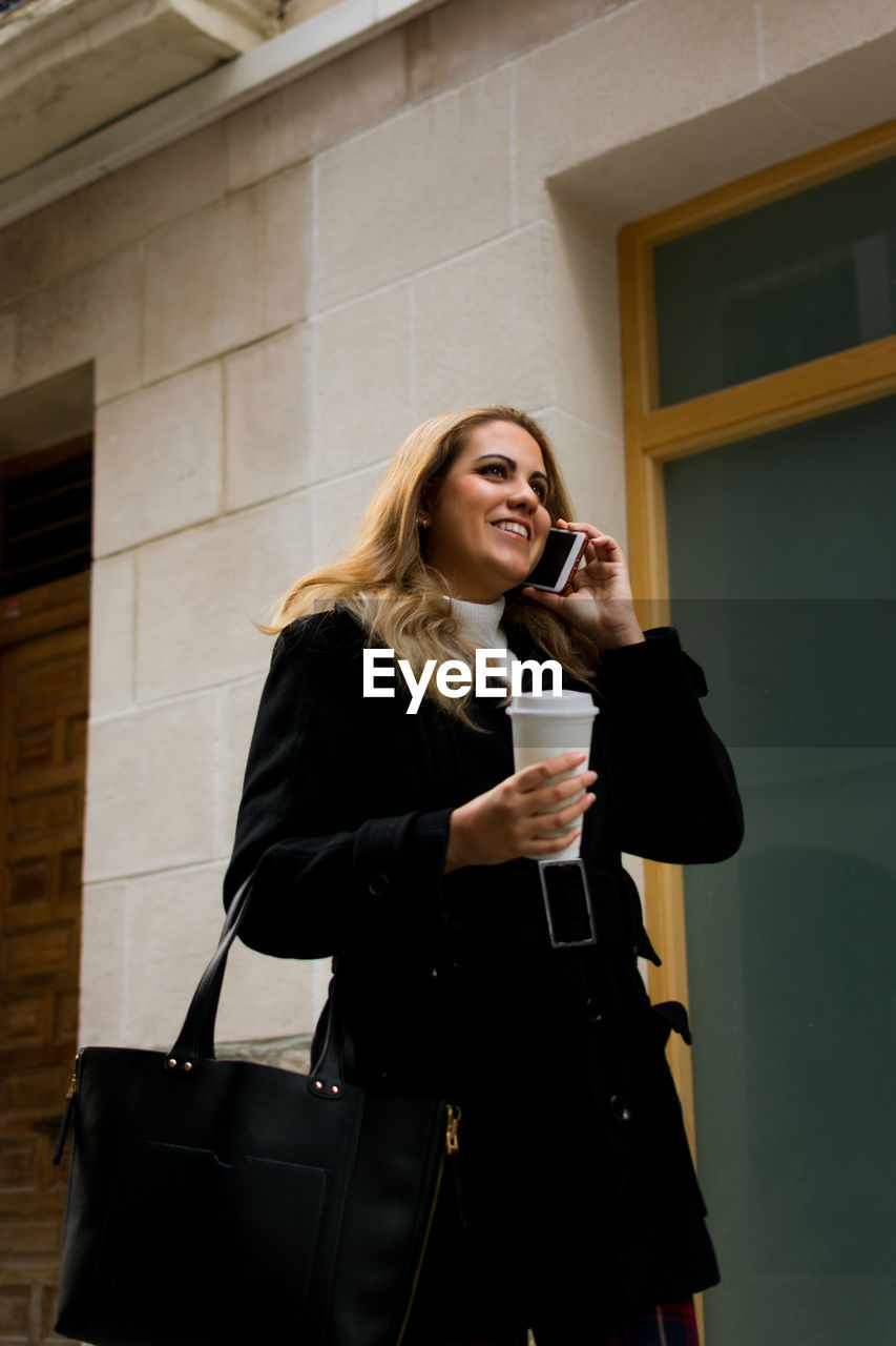 Young woman talks on her phone while walking down the street