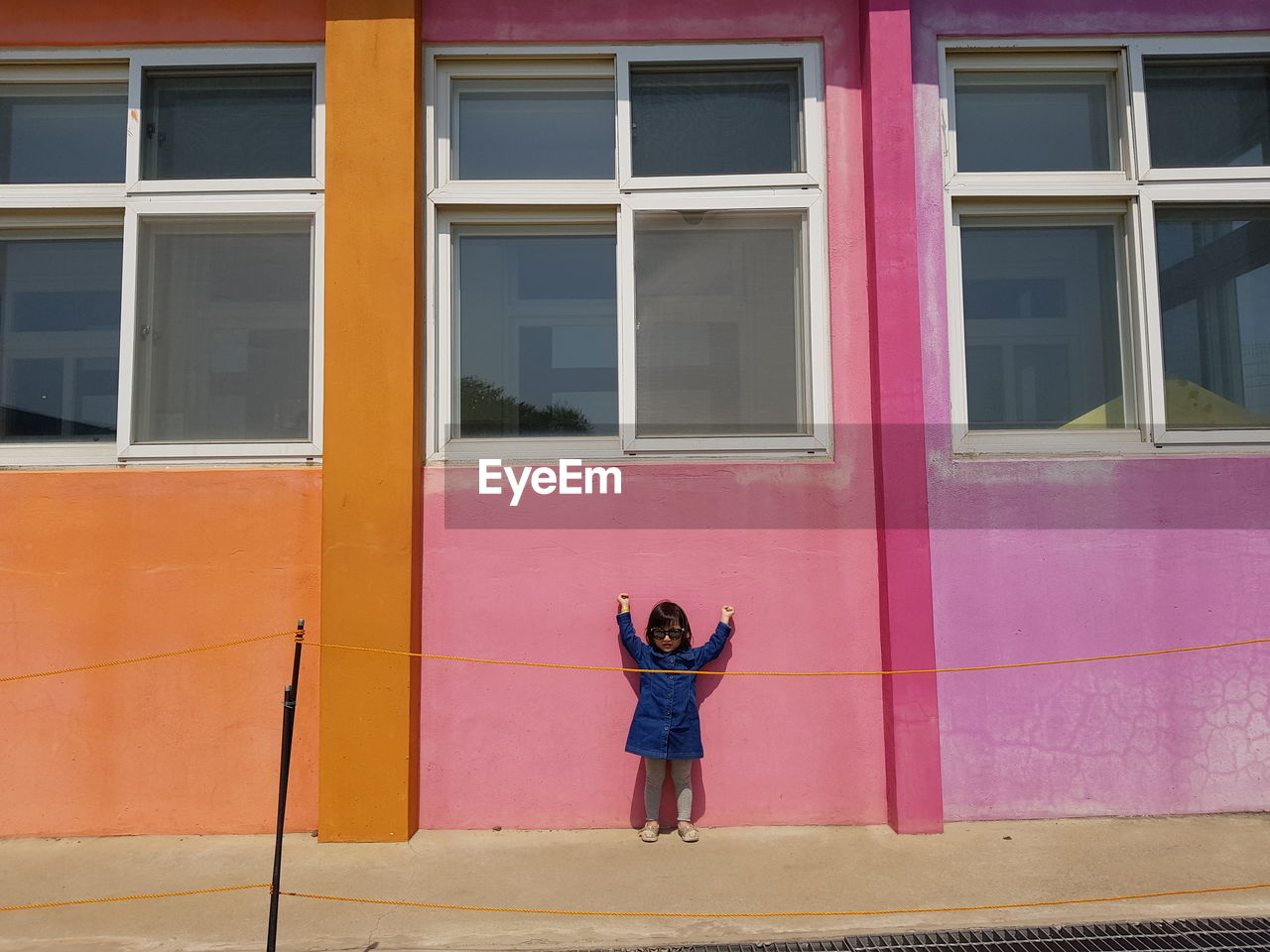 Full length of woman standing by pink building