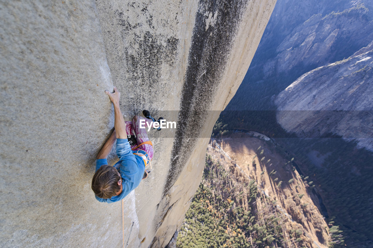 Climbing holding on sideway in crazy position to free climb the nose