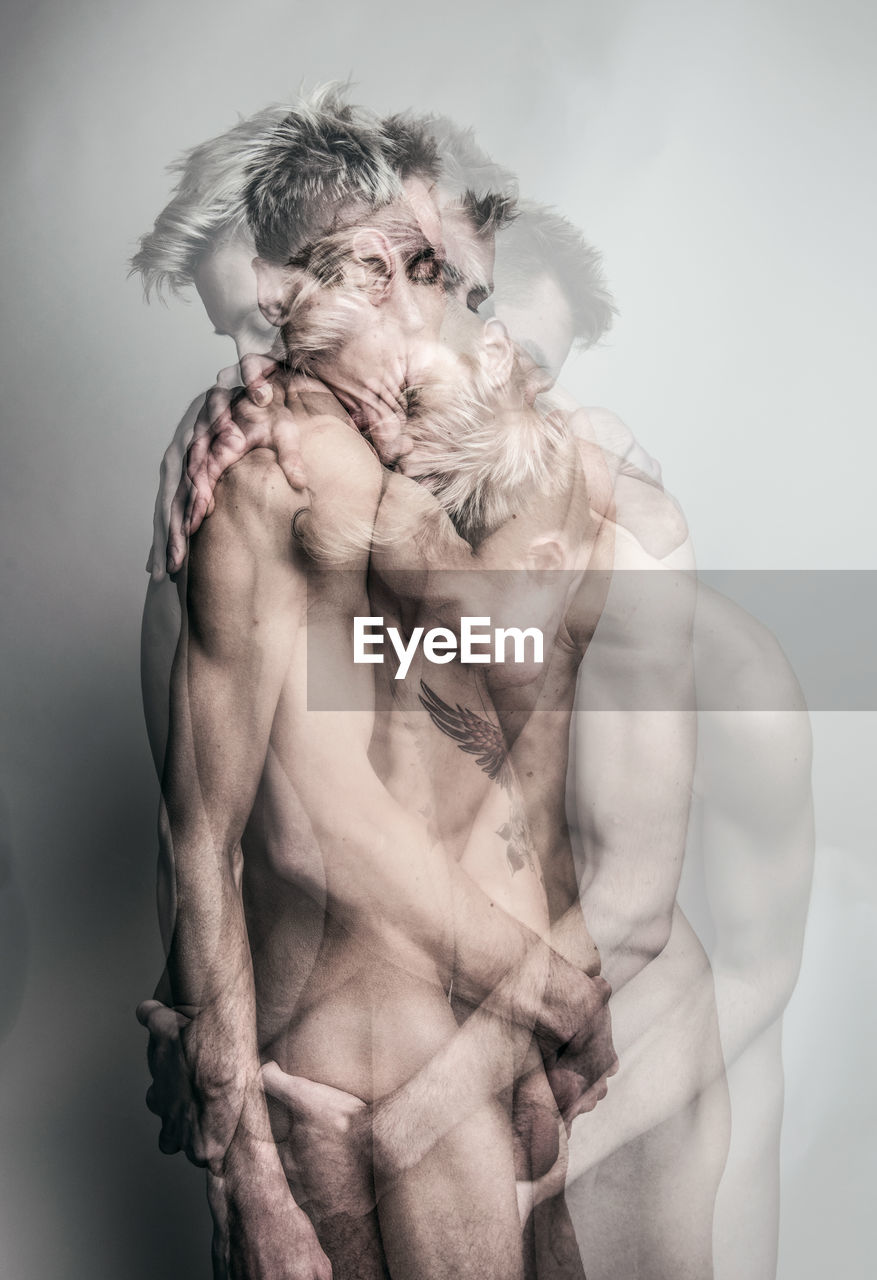 Digital composite image of shirtless gay men embracing against gray background