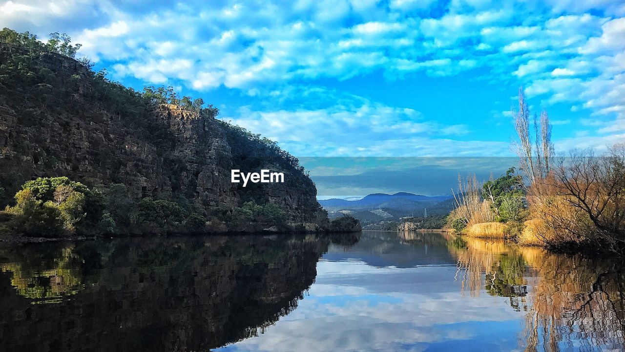 REFLECTION OF TREE AND LAKE AGAINST SKY