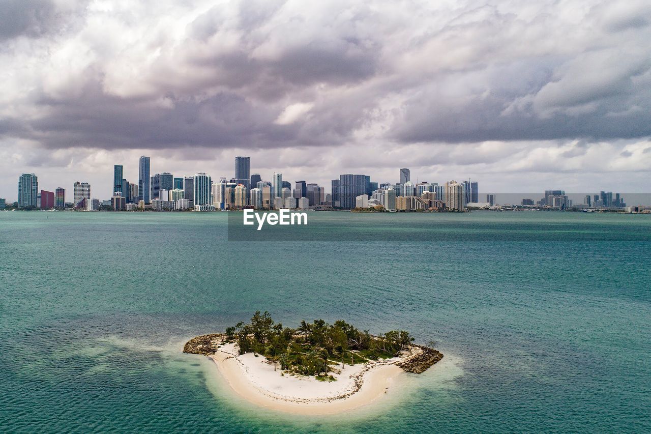 Scenic view of sea and buildings against cloudy sky