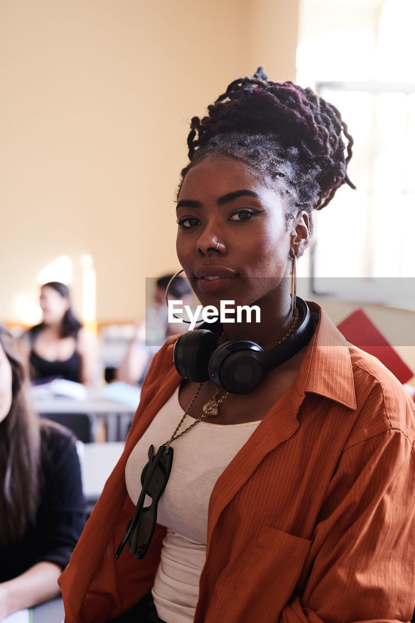 Portrait of confident female student with headphones in classroom