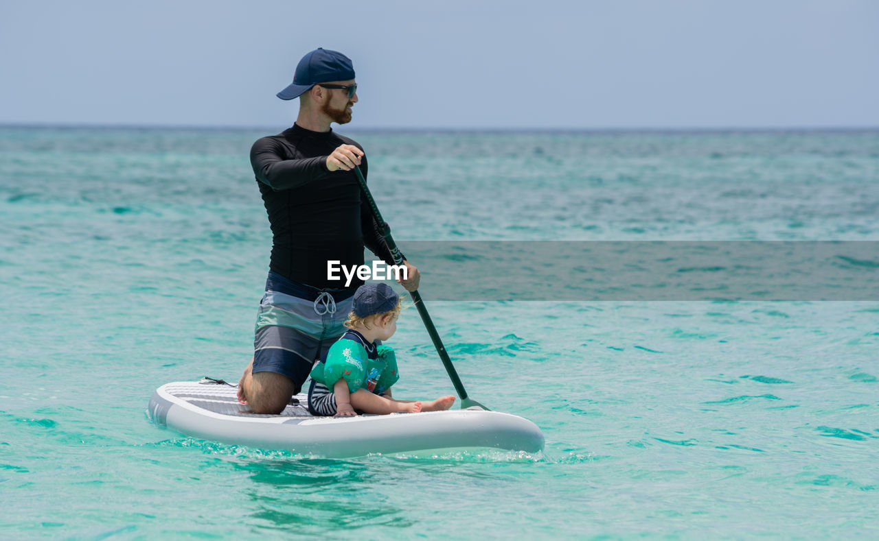 Father and toddler boy on a paddleboard in the ocean