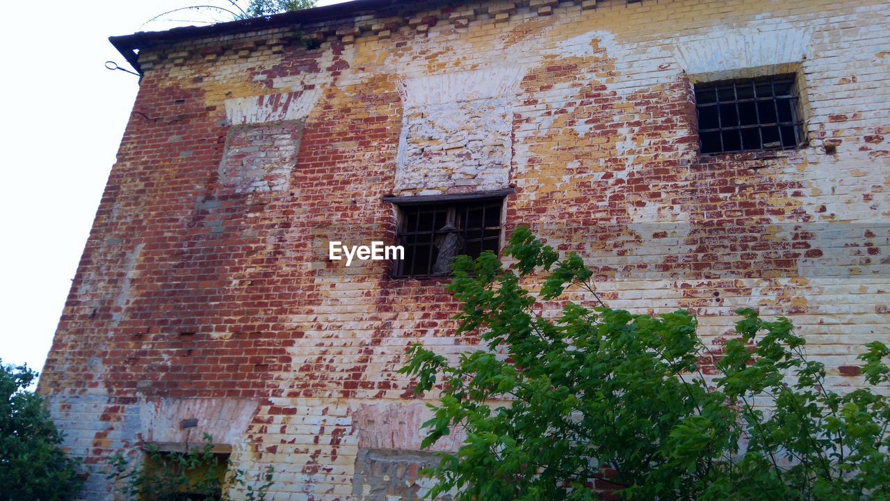 LOW ANGLE VIEW OF BRICK WALL WITH WINDOWS