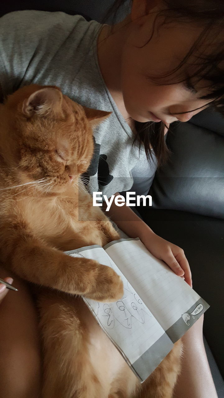 Girl carrying cat while looking at book