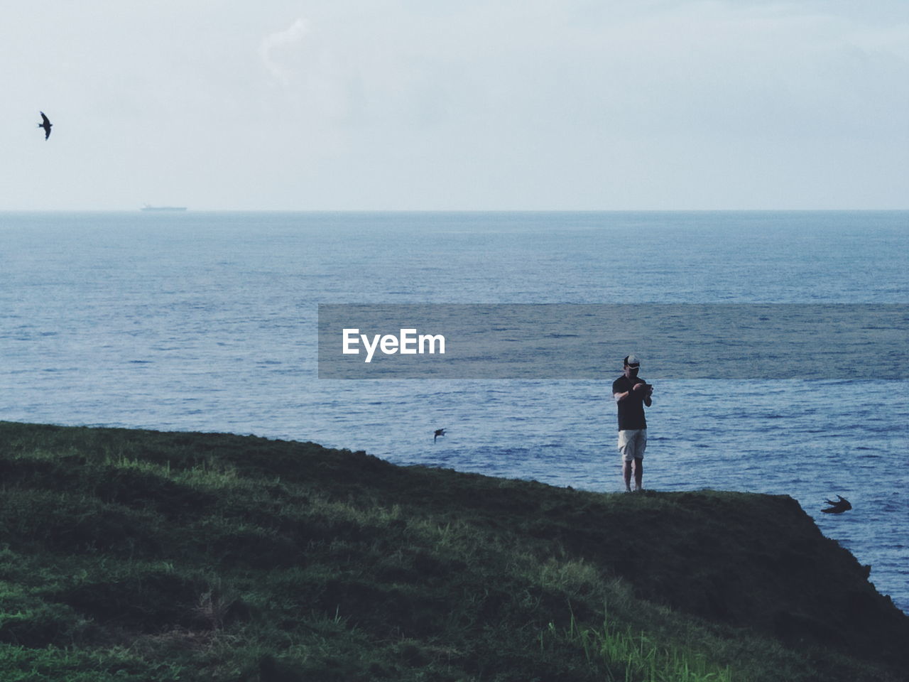 MAN STANDING ON SHORE AGAINST SKY