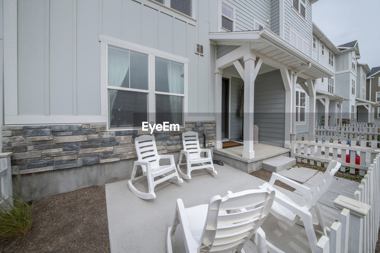 EMPTY CHAIRS AND TABLES BY HOUSE AGAINST BUILDING