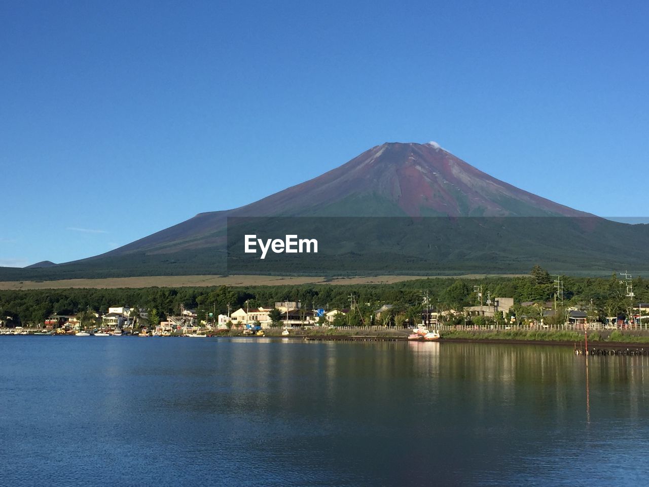 Scenic view of lake and mountains against clear blue sky