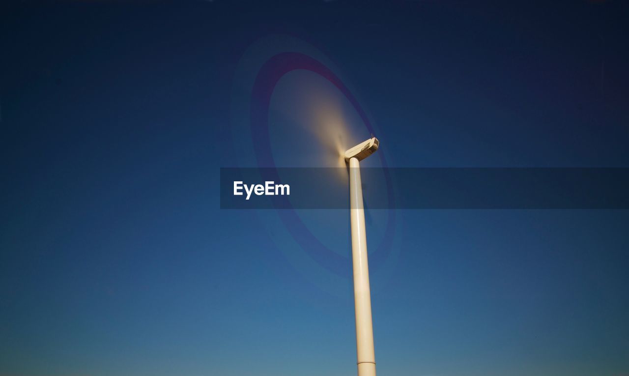 Low angle view of wind turbine against clear blue sky