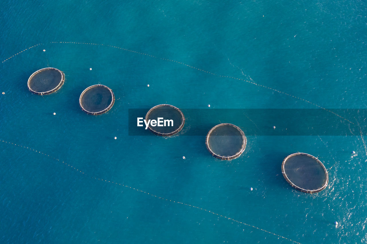 Aerial view of row of fish farms floating in blue water