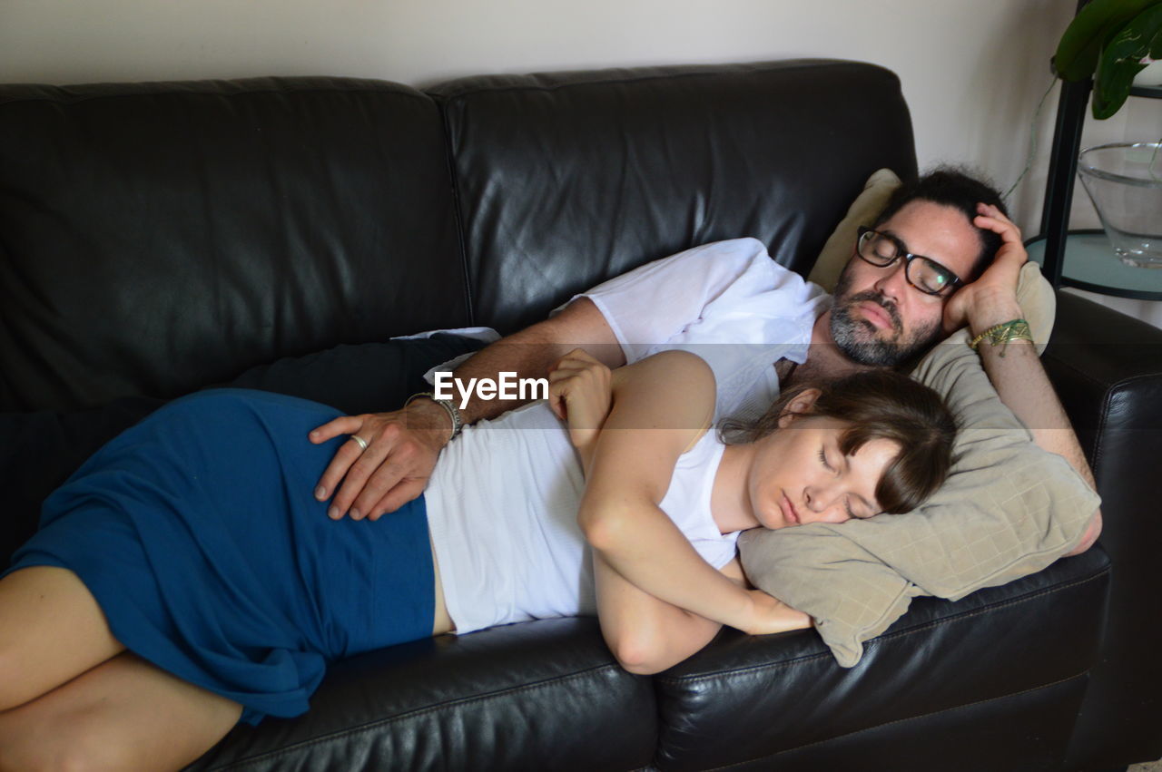 Couple sleeping on sofa at home