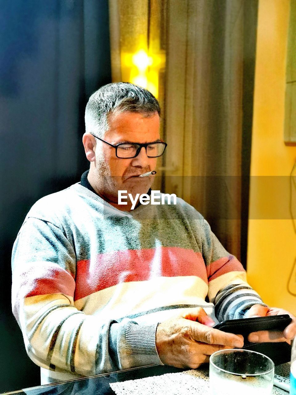 MIDSECTION OF MAN WITH EYEGLASSES SITTING IN TABLE