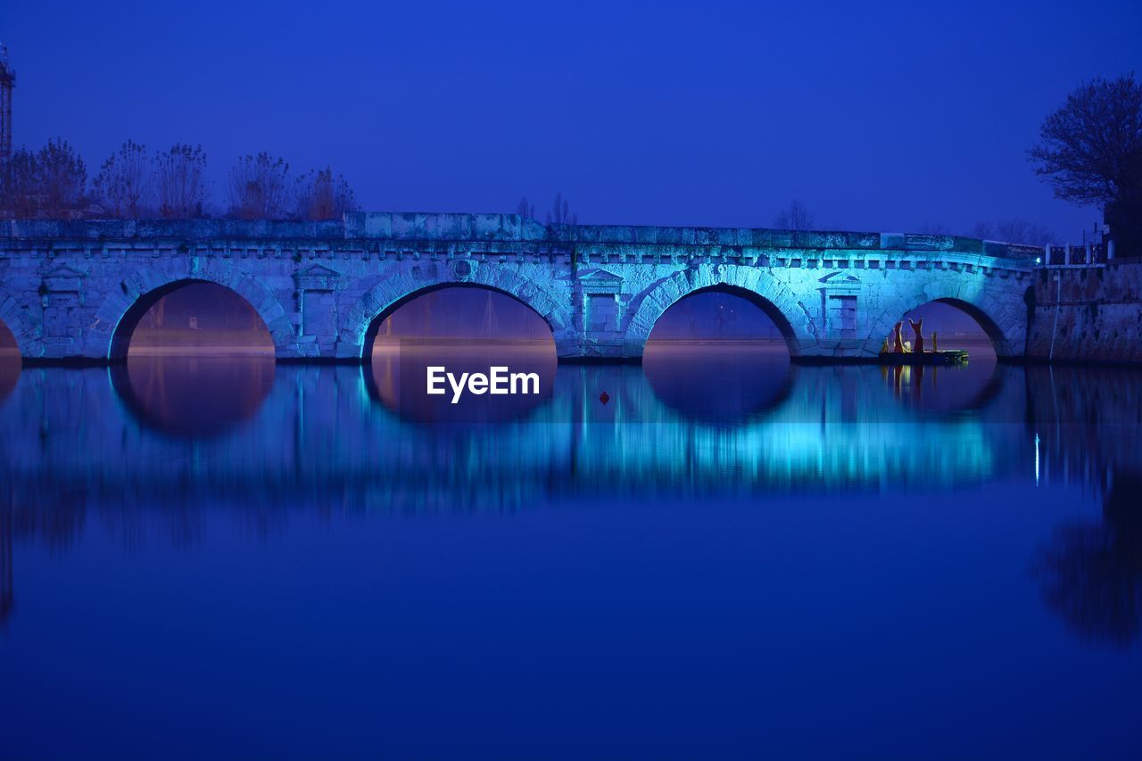 Bridge over river against clear blue sky at night