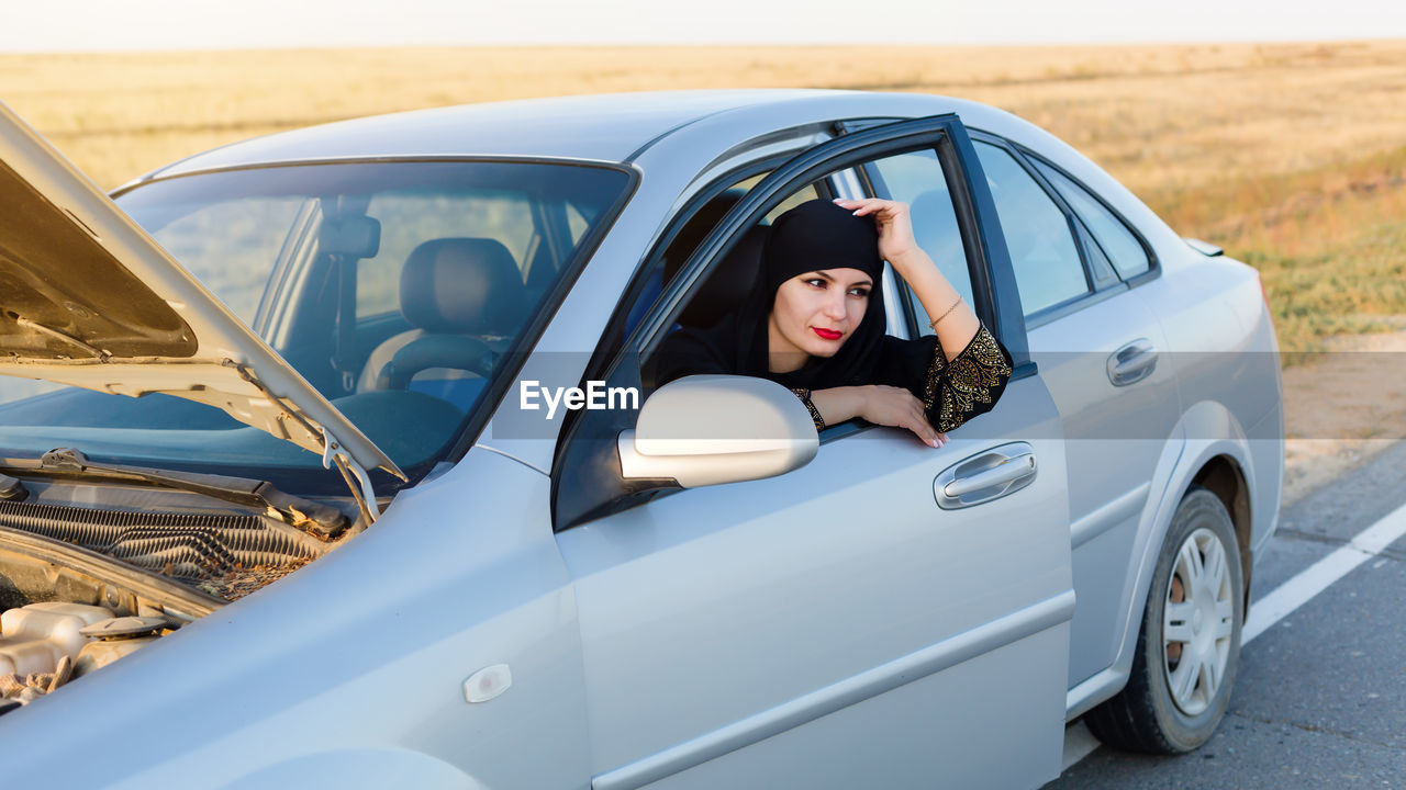 Smiling woman looking away while sitting in car