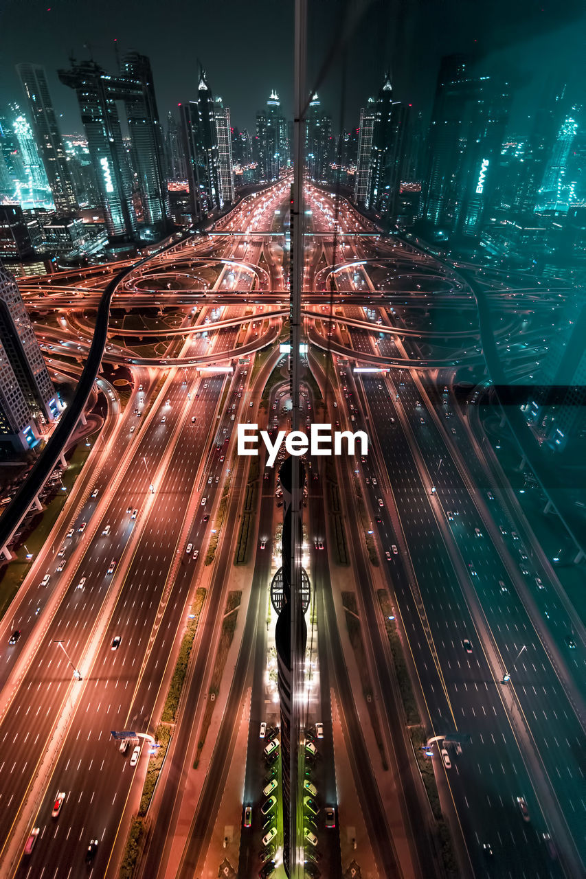 High angle view of light trails on road against buildings at night