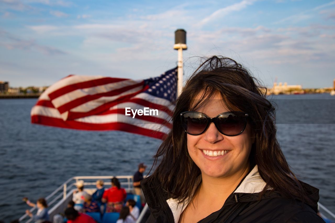 PORTRAIT OF SMILING YOUNG WOMAN AGAINST SEA