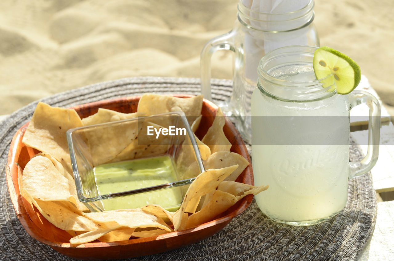 Overhead view of still life green salsa, tortilla chips, lime garnished lemonade baja , mexico