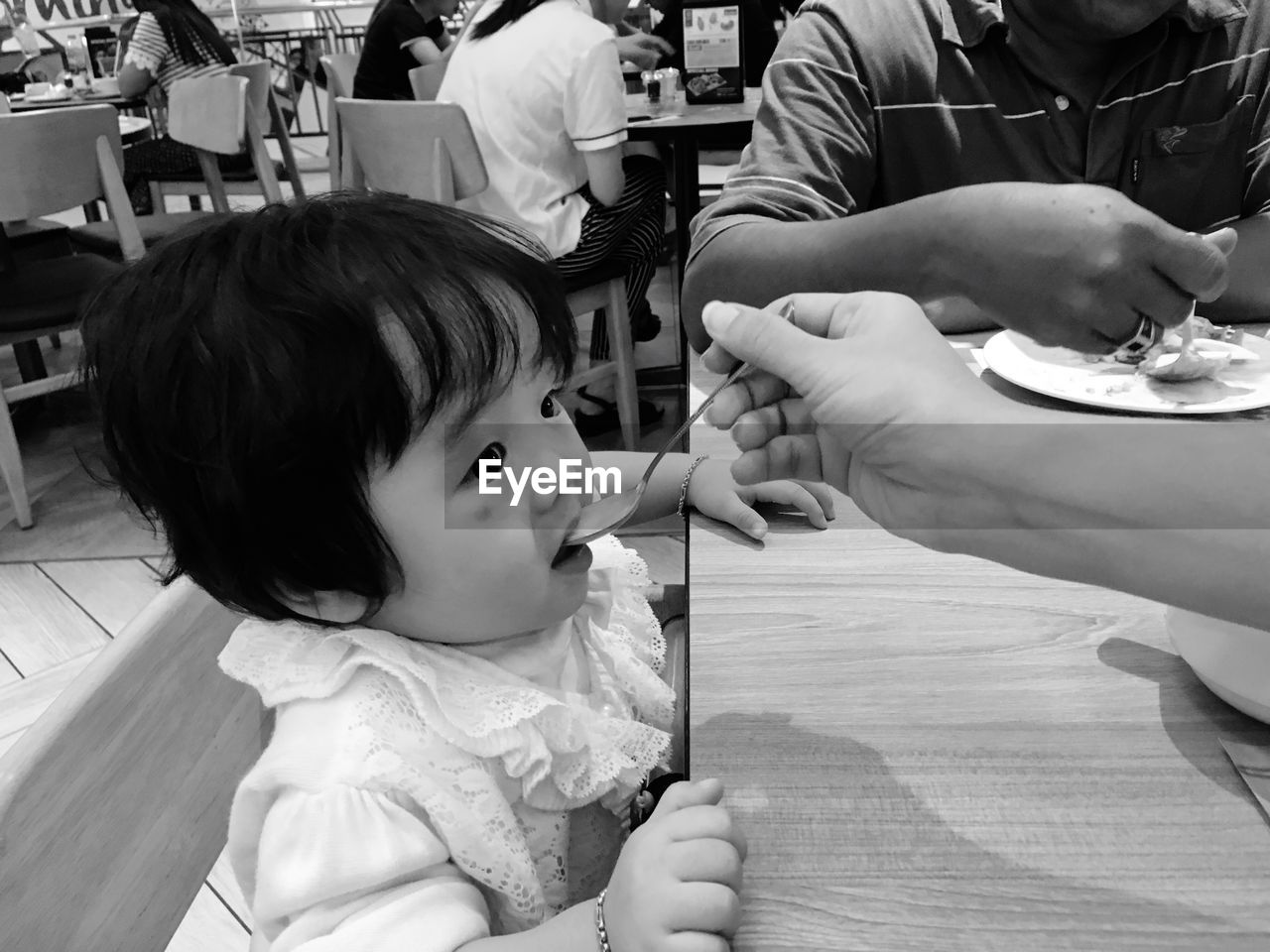 Cropped hand of mother feeding daughter in restaurant