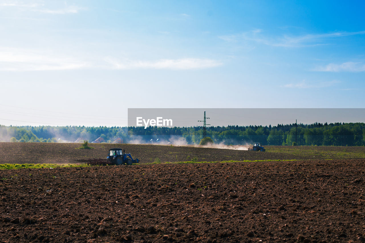 Tractor on agricultural field against blue sky